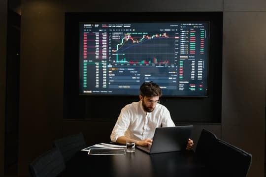 pexels-photo-7567432 Businessman using laptop in office analyzing stock market charts. Professional finance and investment concept.
